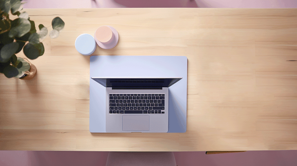 Decluttering can help you feel less distracted while working from home! Picture of a desk with a laptop and a plant, no clutter.